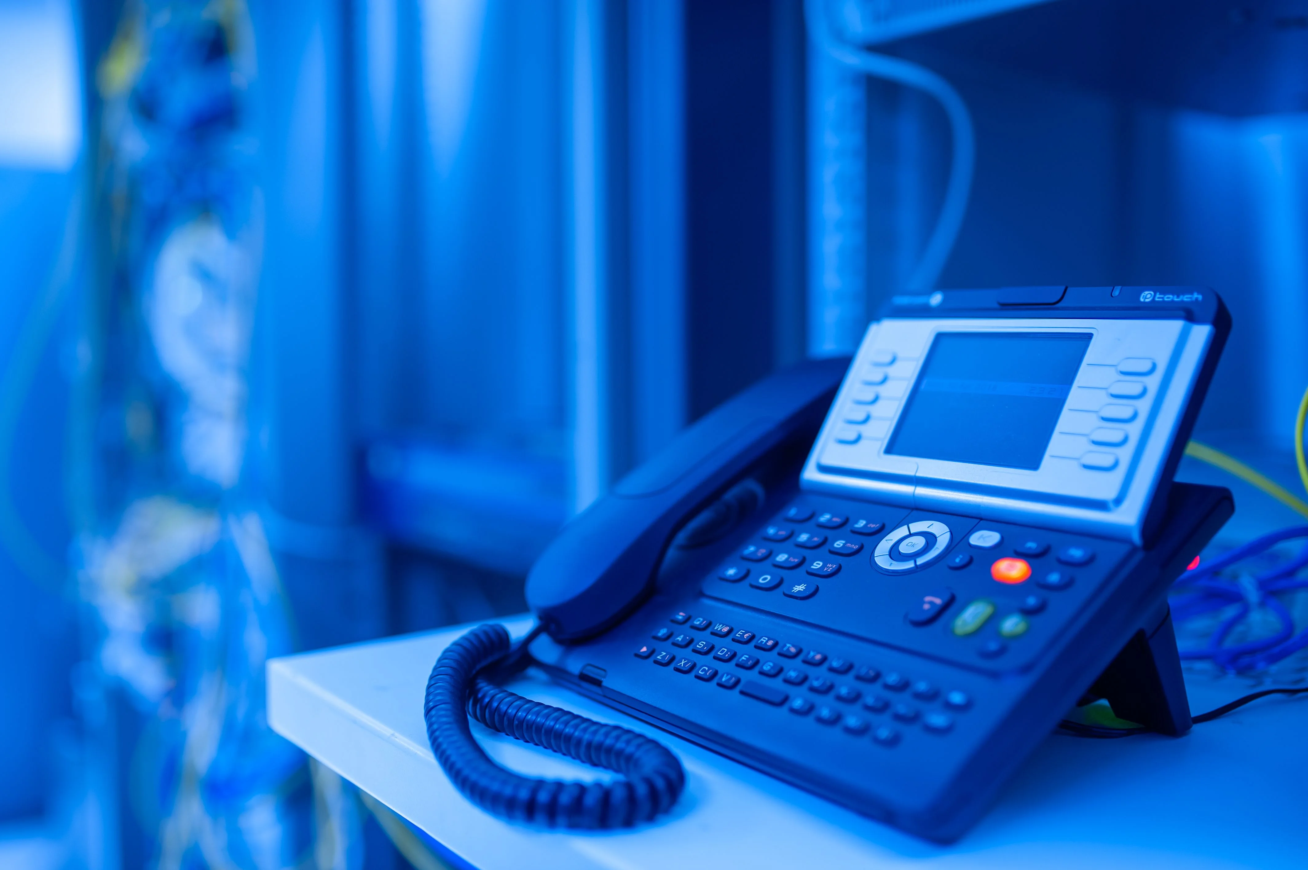 Téléphone IP devant une baie réseau de cabinet dentaire, maintenue par Tech & Smile à Lyon